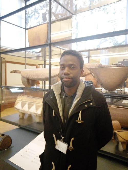 François Makanga devant des tambours à fente dans la salle « Langues et musiques » (Adiac)